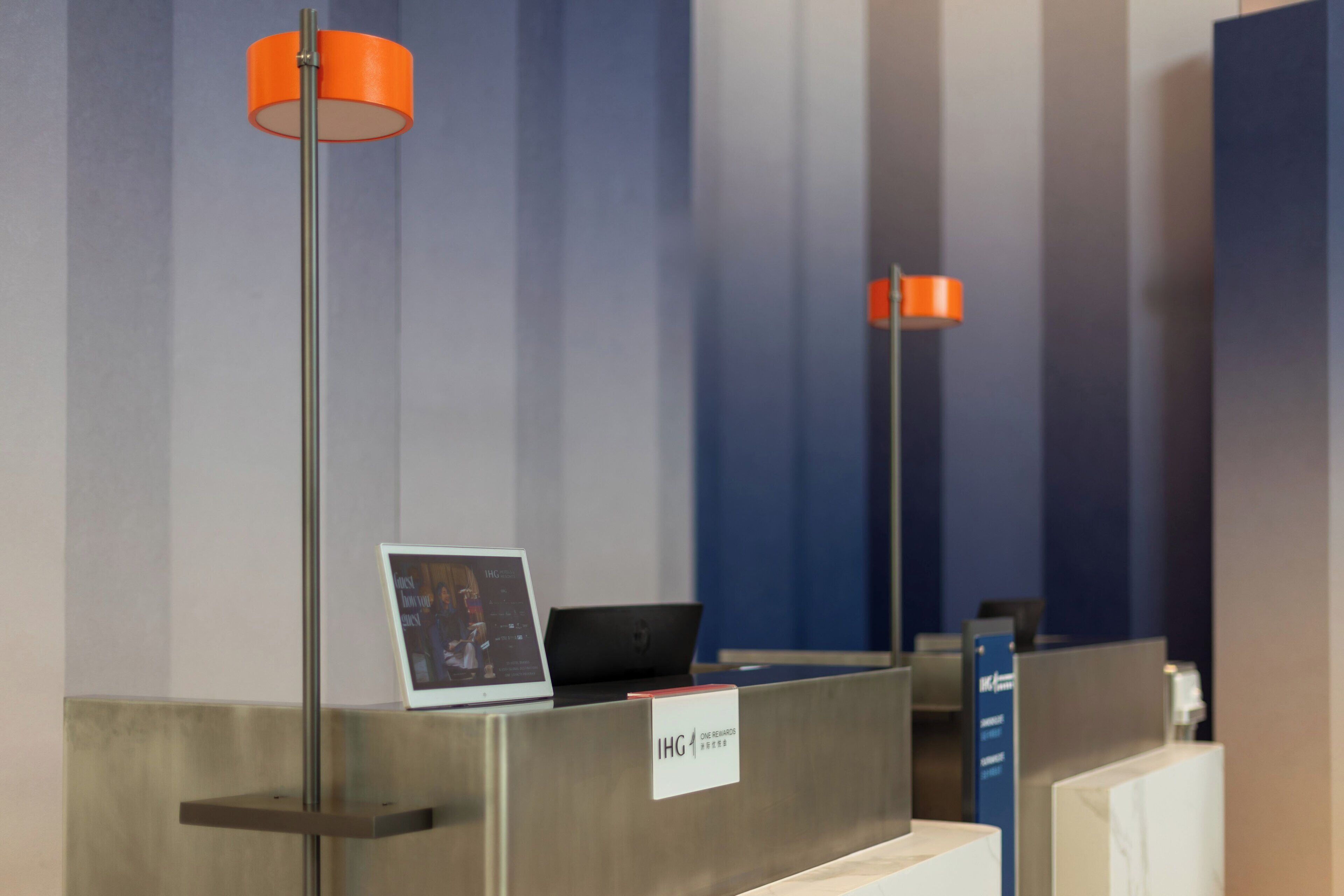 Un mostrador de recepción con una computadora portátil, un cuadro enmarco y un cartel que dice 'IHG'.