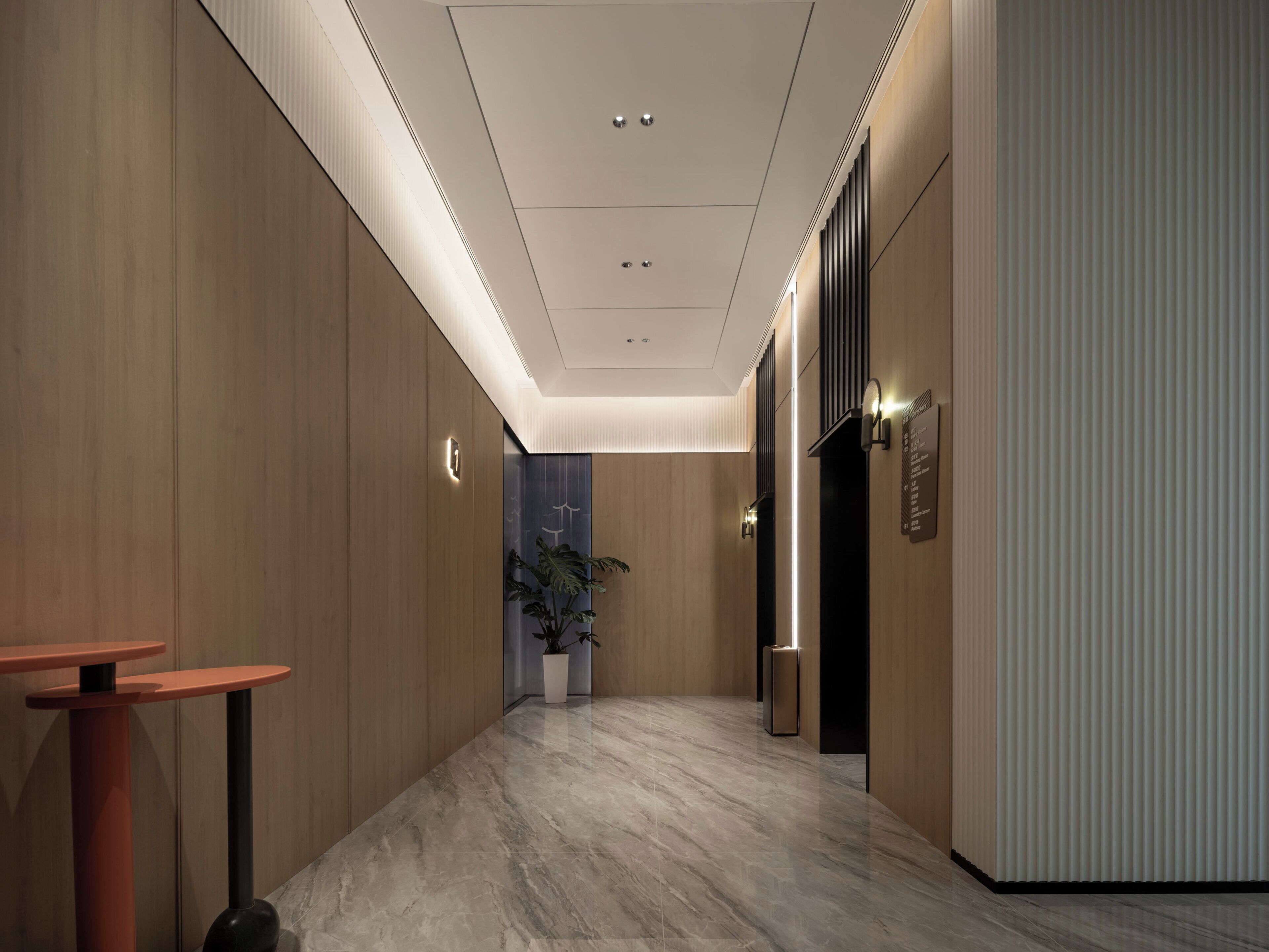 A modern hallway with wooden paneling, a marble floor, and a potted plant.