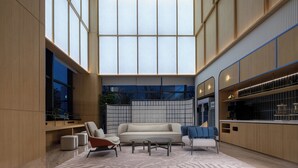 A spacious interior with a high ceiling, large windows, a sofa, chairs, a coffee table, and a kitchen area. - Holiday Inn Express Suzhou SIP Suliu Road by IHG (Suzhou)