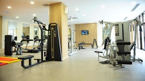 A well-lit gym with various exercise equipment, a television, and a large mirror.