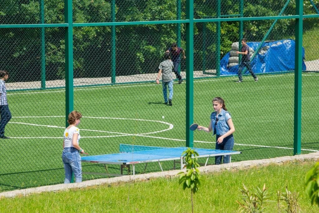 Um campo esportivo com uma mesa de tênis de mesa e uma rede.