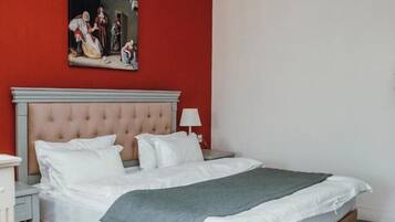 A bedroom with a large bed, a nightstand, a lamp, and a painting on the wall.