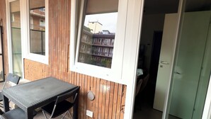 En uteplats med ett bord och stolar, träpanel, ett fönster och en skjutdörr i glas.