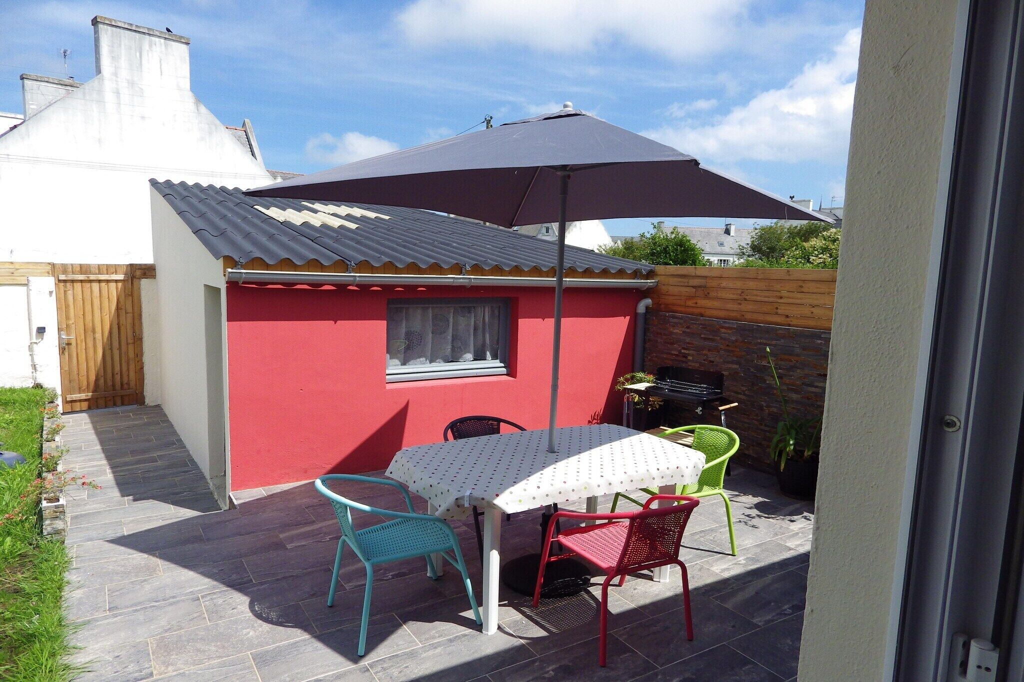 A patio with a table and chairs, a red building, and a large umbrella.