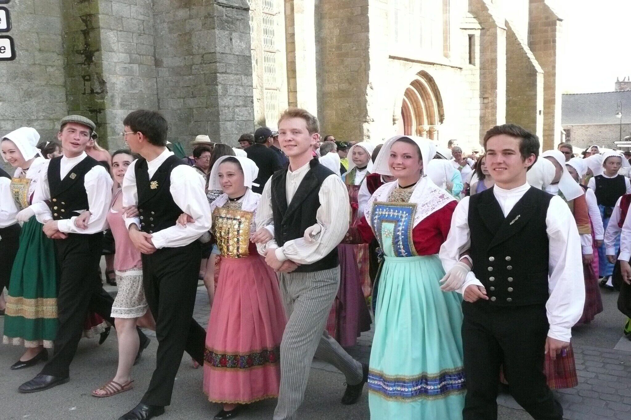 A group of people in traditional attire walking in front of a historic building.