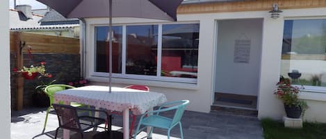 A patio with a table and chairs, a large umbrella, and potted plants.