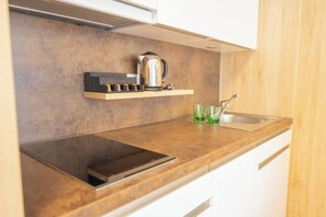 Una cocina moderna con estufa integrada, hervidor y un recipiente de vidrio sobre la encimera.