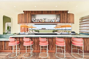 Zona de bar con mostrador de madera, varios taburetes y vistas a la ciudad.