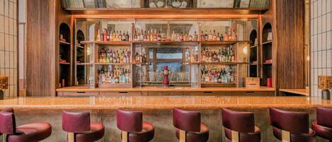 Een bar met meerdere flessenrekken, een bar en verschillende barstoelen.