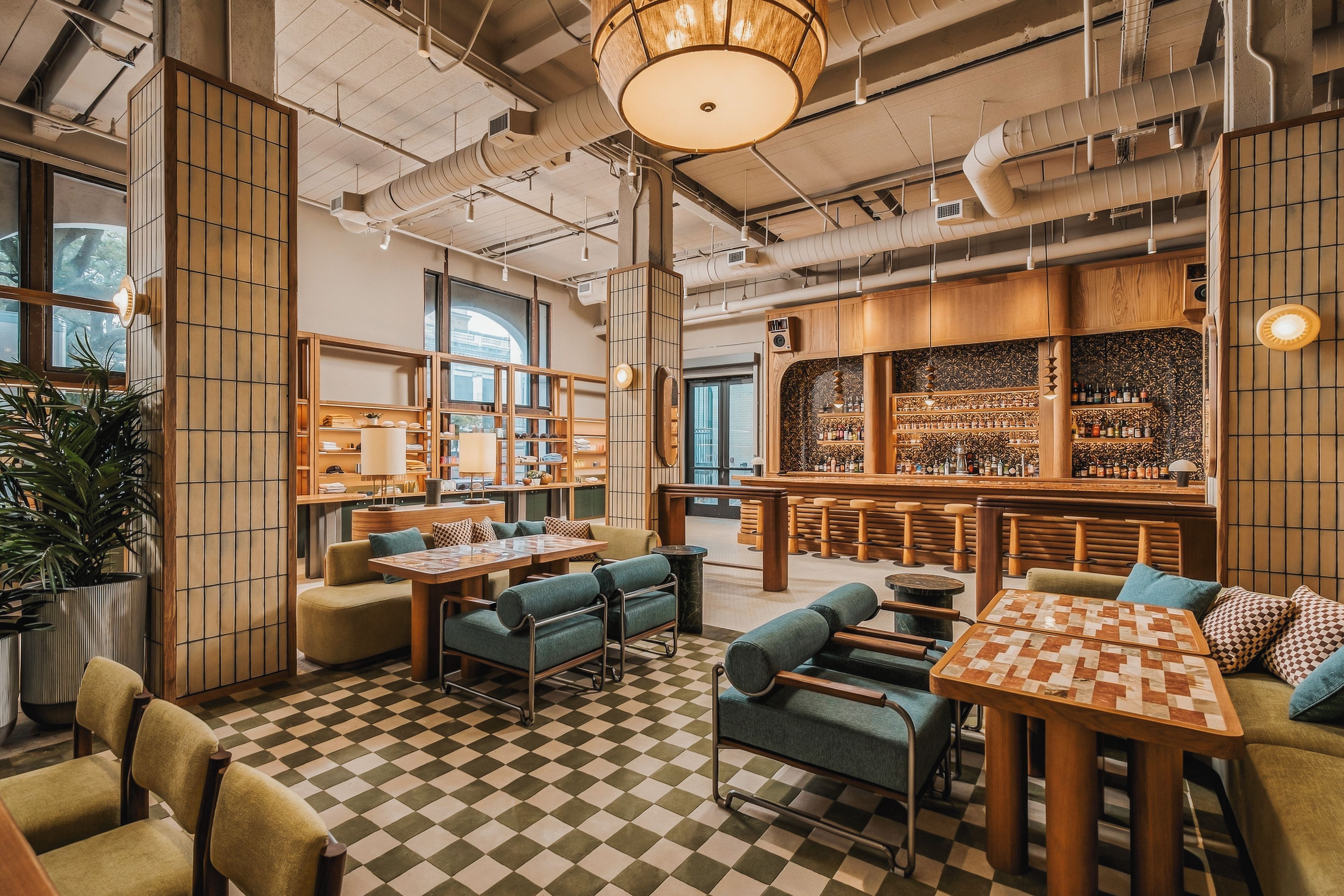 A spacious cafe with checkered flooring, wooden furniture, and a bar area with shelves of bottles.