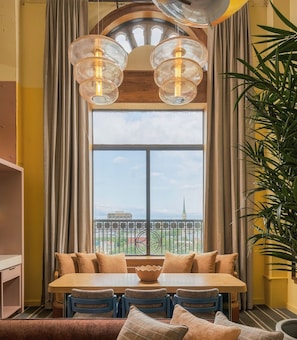 Un coin repas avec une grande fenêtre, une table avec des chaises et un luminaire suspendu.
