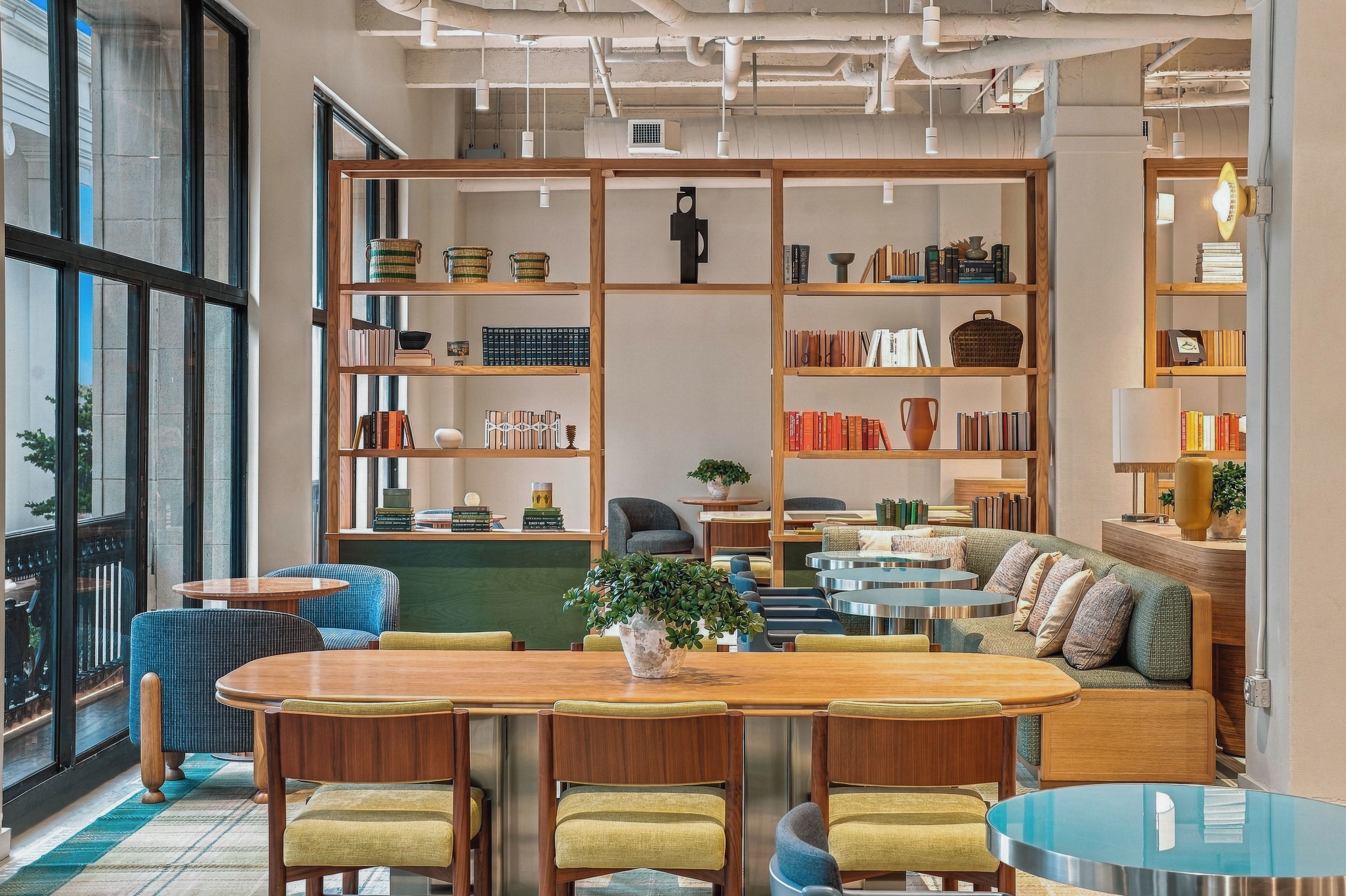 A modern library with bookshelves, seating areas, and a large window.