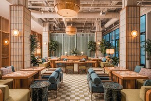 A spacious lounge area with checkered flooring, wooden furniture, and green plants. - Recess Hotel and Club (Savannah)
