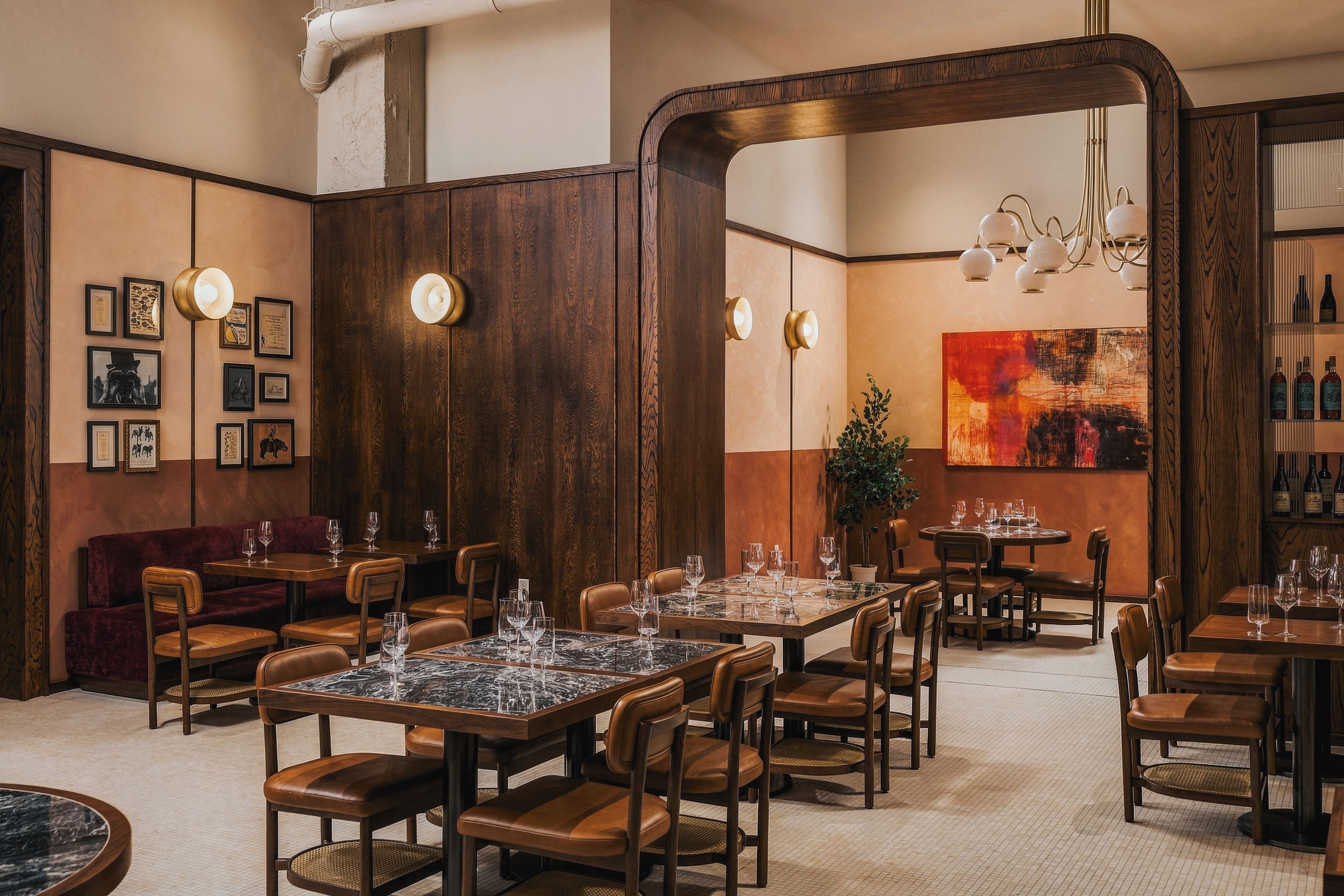 A restaurant interior with wooden paneling, framed artwork, and a variety of seating arrangements including tables and booths.