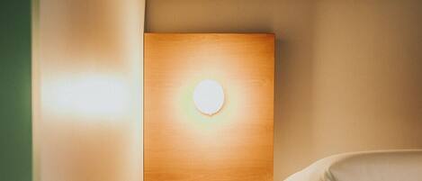 A compact, modern room with a wooden staircase leading to a bed, a built-in radio, and a circular light fixture.