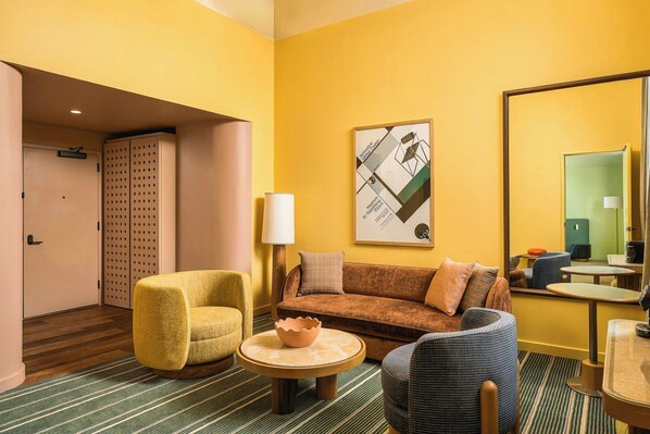A hotel room with a sofa, two armchairs, a small table, a lamp, and a framed picture on the wall. - Recess Hotel and Club (Savannah)