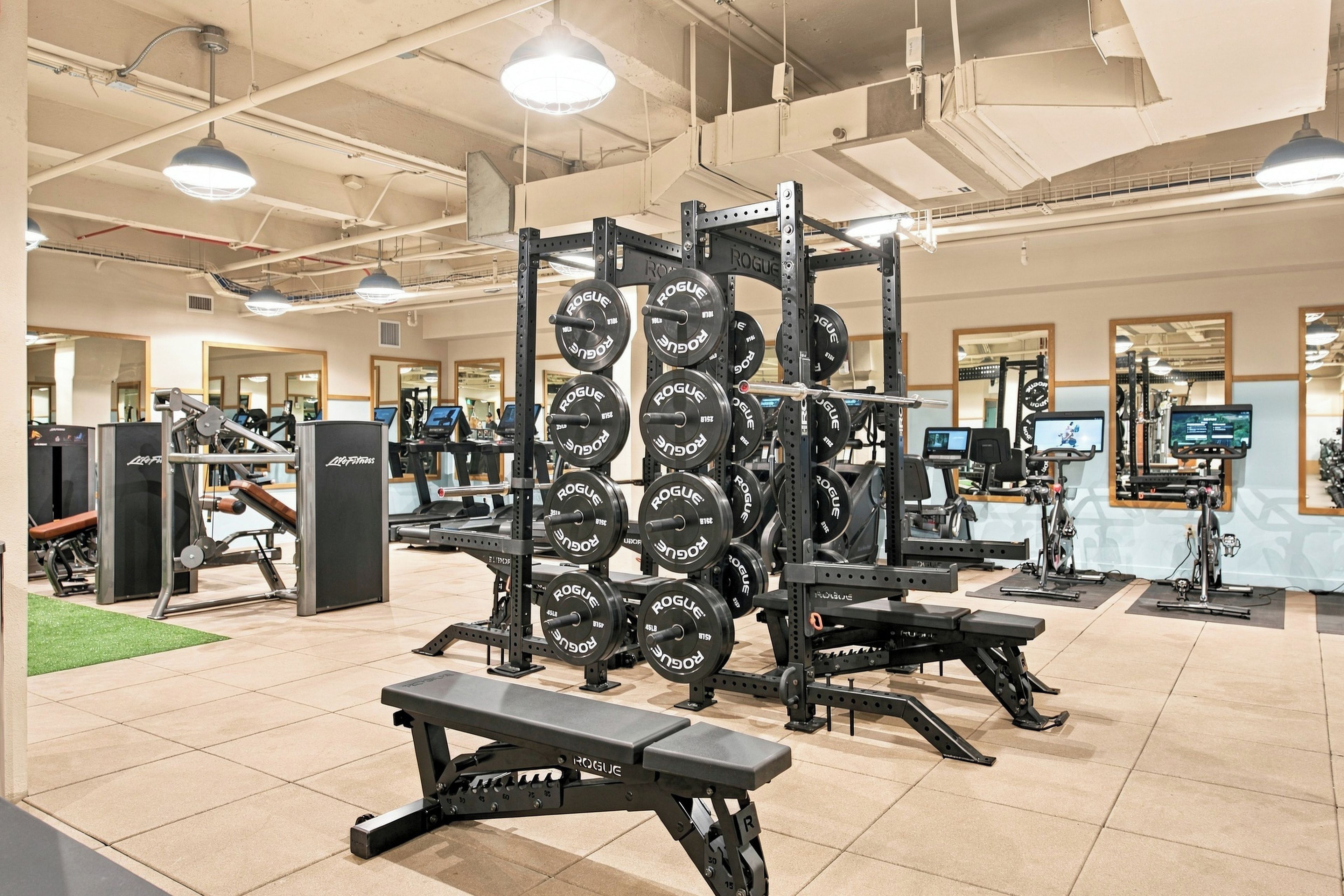 A gym with weightlifting equipment, treadmills, and exercise bikes.