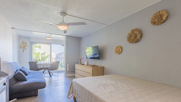 Ein modernes Schlafzimmer mit Bett, Sofa, Fernseher und Deckenventilator.