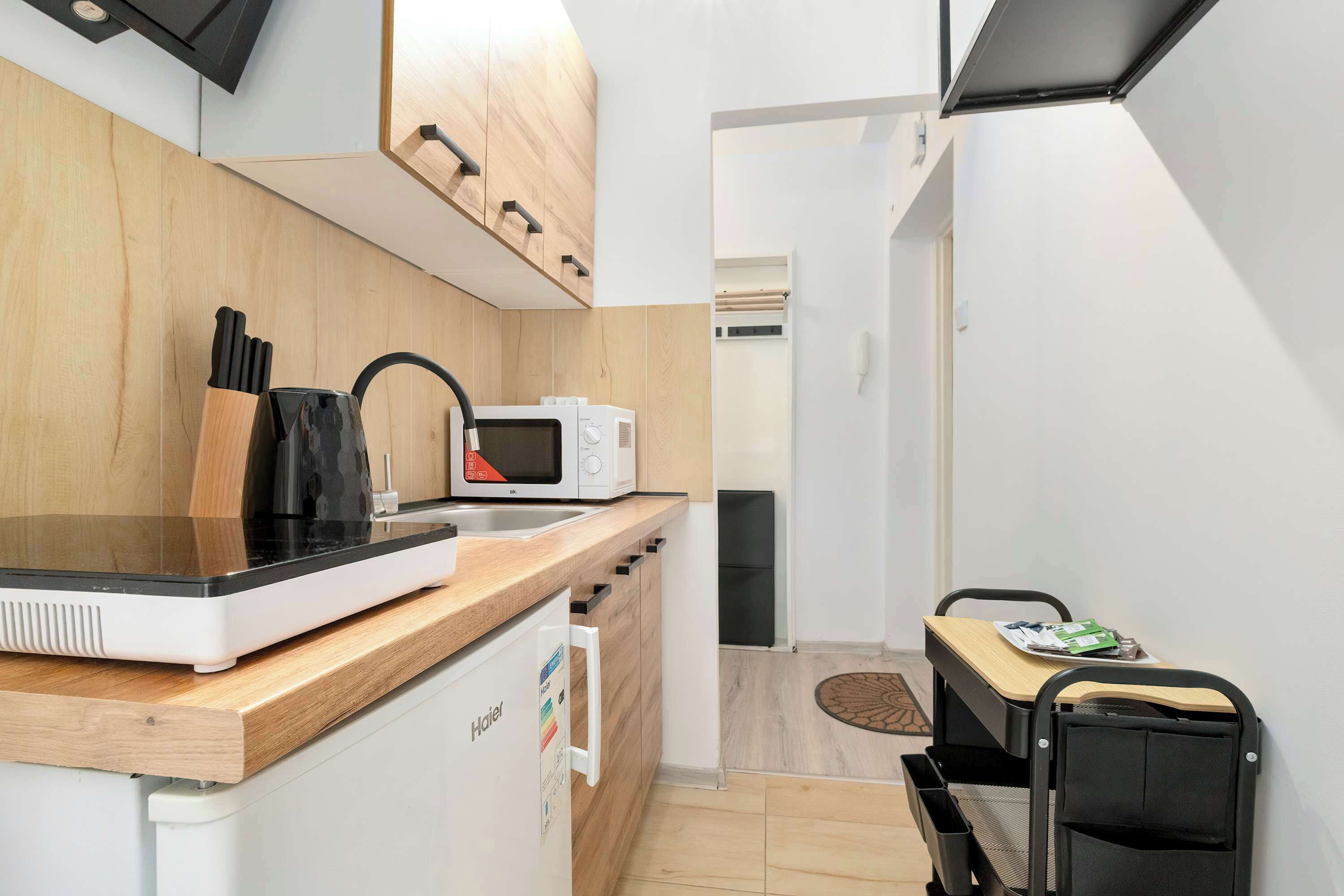A compact kitchen with a microwave, toaster, and wooden countertop.