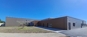 A modern building with a flat roof, large windows, and a paved entrance area. - Kyriad Prestige - Pierrelatte (Pierrelatte)