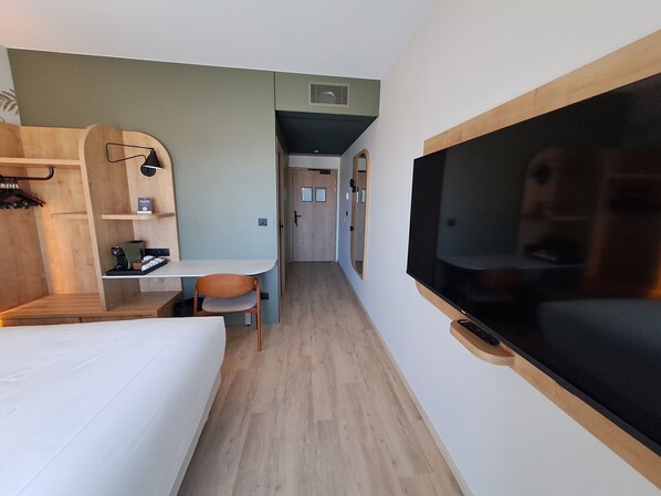 Une chambre d’hôtel de taille réduite, comprenant un lit, un bureau, une chaise et un téléviseur.
