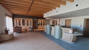 A modern lobby with a wooden ceiling, seating area, reception desk, and built-in shelving. - Kyriad Prestige - Pierrelatte (Pierrelatte)
