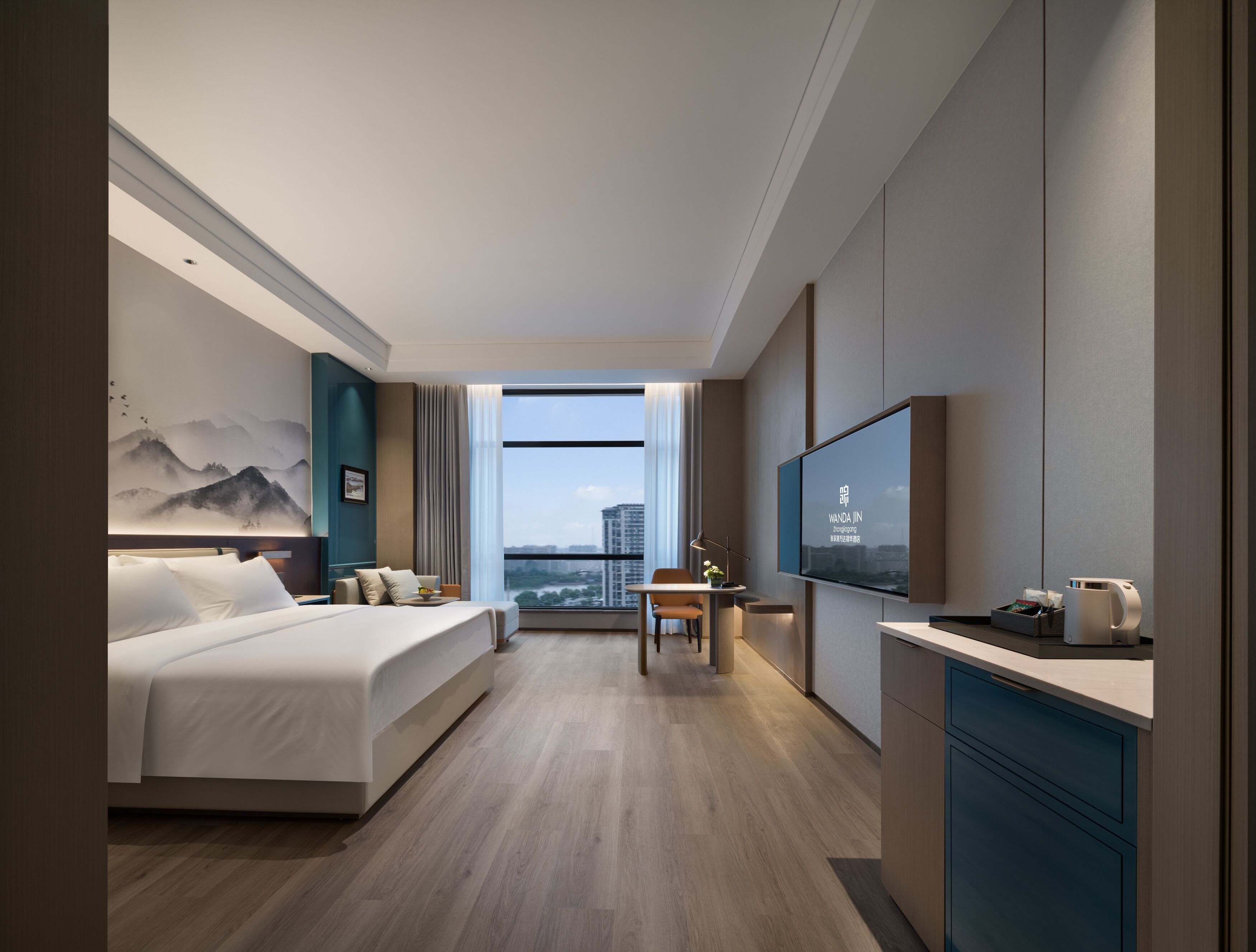 Quarto de hotel moderno com uma cama grande, escrivaninha, televisão e vista da cidade.