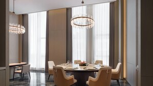 Een moderne eetkamer met een ronde tafel, zes stoelen en een kroonluchter.