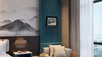 Una habitación de hotel moderna con cama, sofá, mesa de centro y un gran ventanal con vistas.