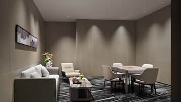 Een moderne hotelkamer met een bank, fauteuils, een eettafel en een salontafel.