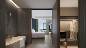 Een moderne hotelkamer met een badkuip, een bed, een televisie en een inloopkast.
