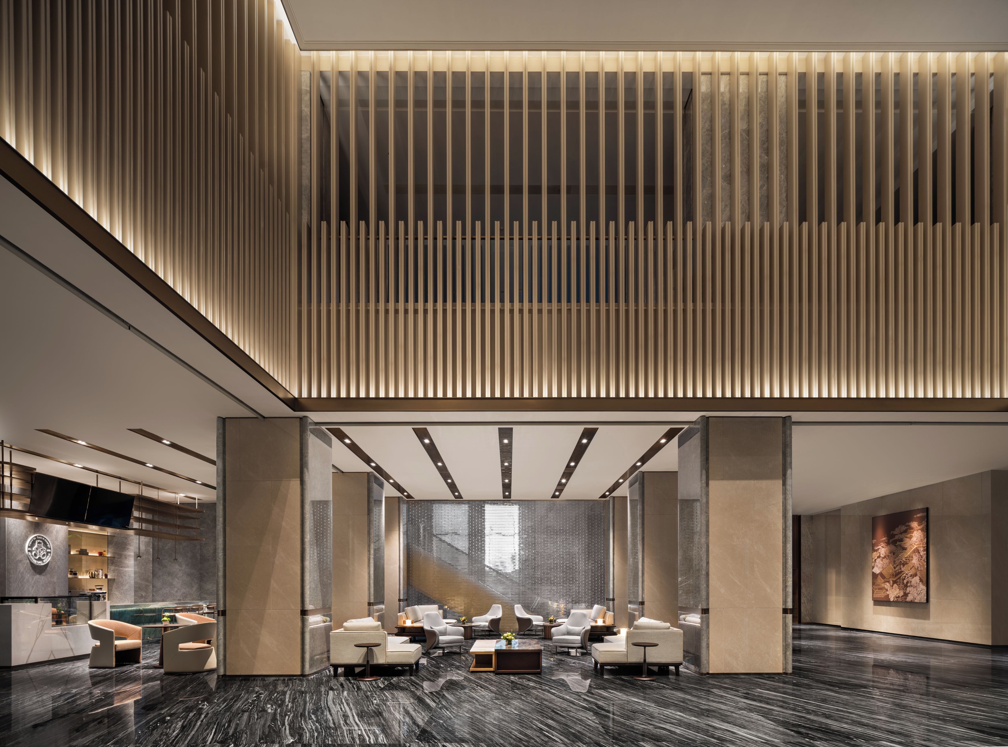 A modern lobby with a reception desk, seating area, and a large window.