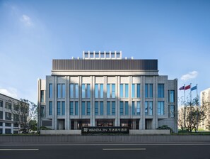 Un bâtiment moderne avec une enseigne indiquant « Wanda Jin » et un drapeau.