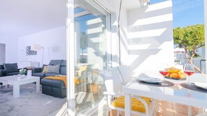 A modern living room with a sofa, coffee table, and a glass partition. - Apartment in Cancelada Near the Beach (Estepona)