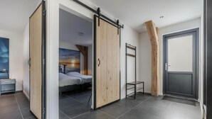 Une chambre moderne avec une porte coulissante, un lit, une petite table et une échelle.