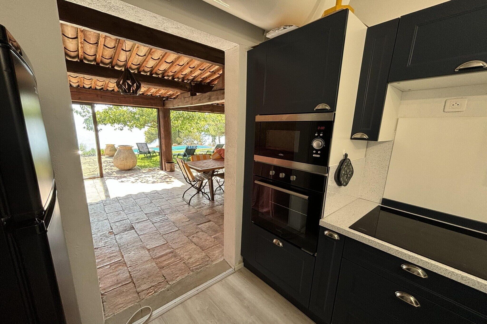 A kitchen with dark cabinets, a built-in oven, and a countertop.