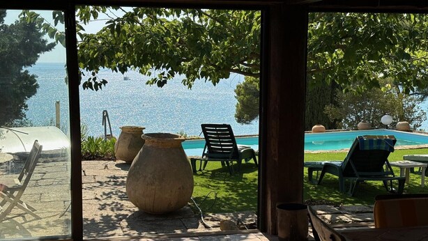 Eine Terrasse mit Sitzgelegenheiten im Freien, ein Schwimmbad und Meerblick.