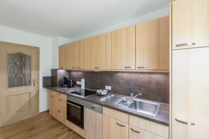 A compact kitchen with wooden cabinets, a stainless steel sink, and a built-in oven. - zwei Appartements im EG für befreundete Familien (Graifenau)