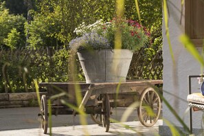 A garden cart with a flower pot on a paved surface, surrounded by greenery. - zwei Appartements im EG für befreundete Familien (Graifenau)