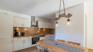 Ett modernt kök med träskåp, en köksö och hängande lampor.