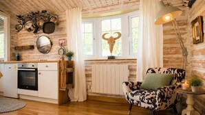 Une cuisine rustique aux murs en bois, avec un fauteuil à motifs de vaches et un décor représentant un crâne de taureau.