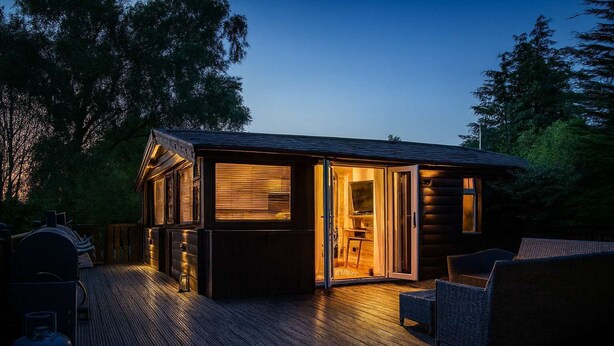 Un chalet confortable avec une terrasse en bois, une cheminée et un téléviseur.