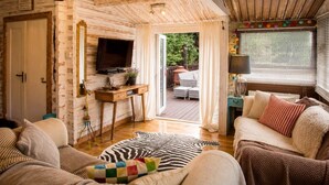 Une pièce confortable avec un plafond en bois, une télévision, un bureau, un canapé et un tapis à motifs zébrés.