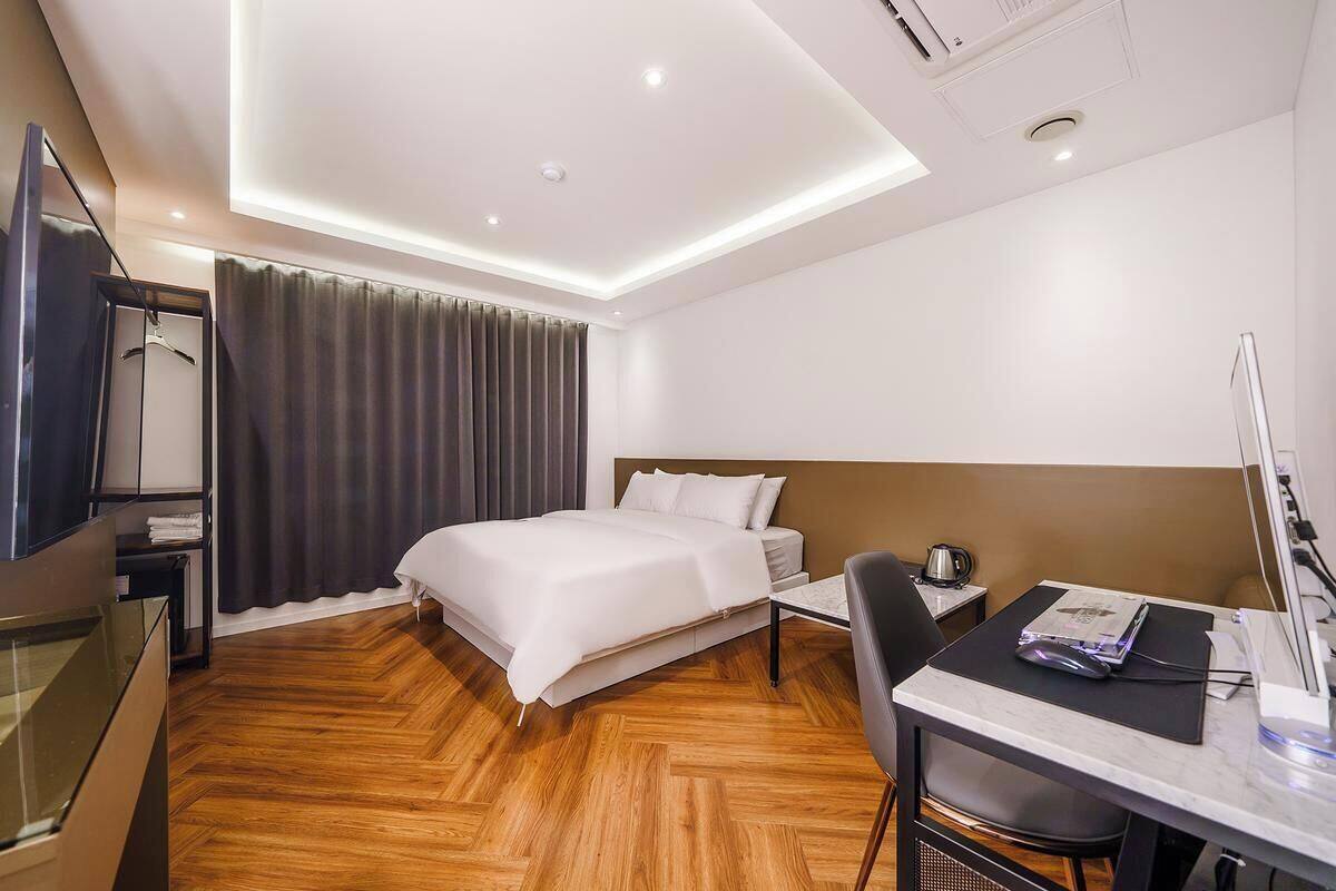 Una camera d'albergo moderna con un letto, un comodino, una sedia, una scrivania e una televisione a schermo piatto.