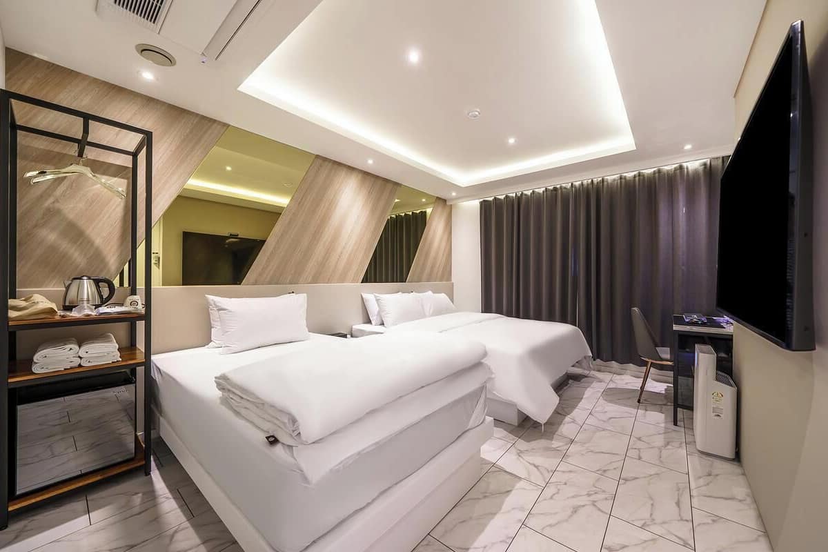Camera d'albergo moderna con un letto grande, una scrivania, un televisore a schermo piatto e uno specchio.