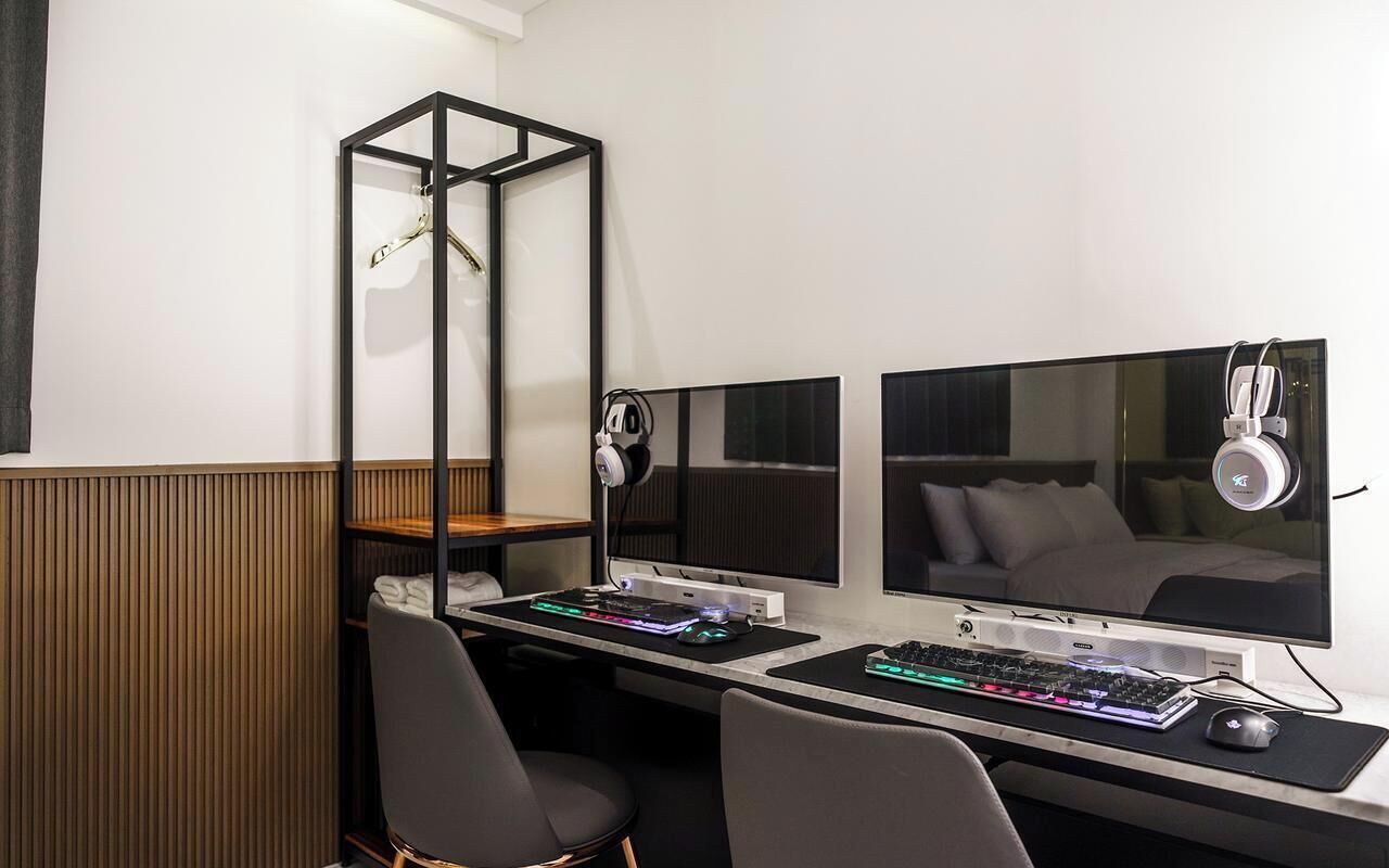 Ett modernt hotellrum med ett skrivbord, två bildskärmar, ett tangentbord och en mus.