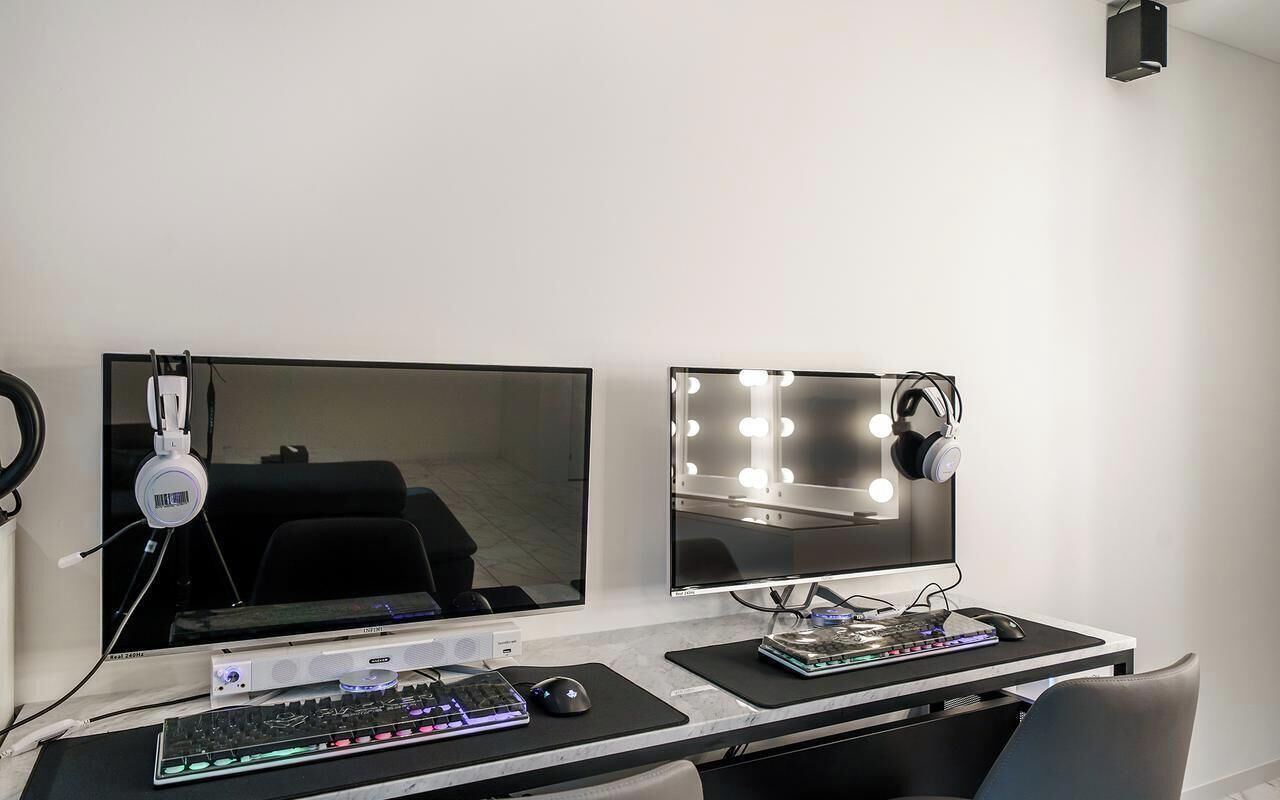 A modern home office setup with dual monitors, a keyboard, a mouse, and a sound mixer.