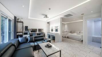 A modern living room with a sofa, coffee table, and a kitchenette area.