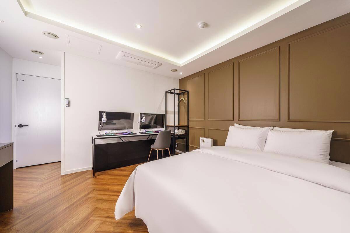 Una camera d'albergo moderna con un letto grande, una scrivania con un computer e una sedia.