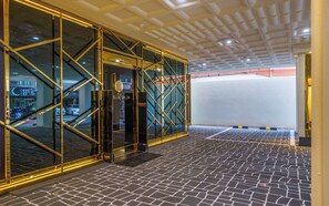 Un intérieur moderne avec une entrée dotée d’une porte en verre, un sol carrelé et un plafond équipé d’un système d’éclairage encastré.